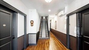 A hallway with wooden flooring, dark walls, and a staircase leading to an upper floor.