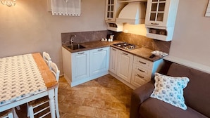 A compact kitchen with a dining table, chairs, a sofa, and a patterned pillow. - L'OCA GIULIVA RELAIS  (Gaggio Montano)