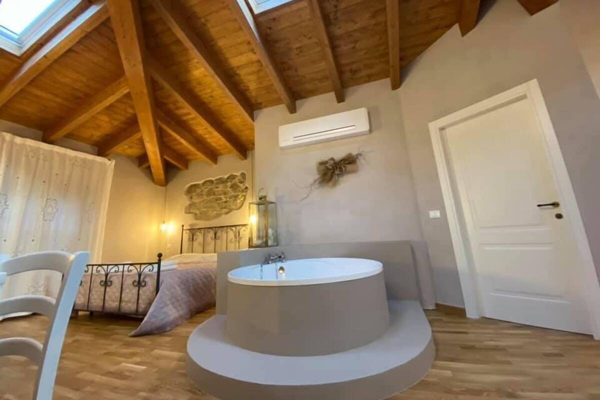 Un baño con una bañera independiente, vigas de madera, un adorno de pared de piedra y una puerta.