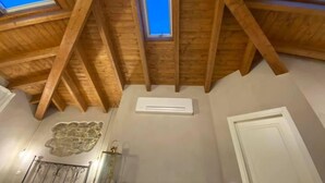 A room with a sloped wooden ceiling, skylights, a stone wall decoration, and a white door. - L'OCA GIULIVA RELAIS  (Gaggio Montano)