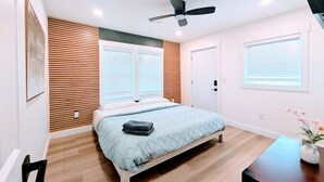 Quarto com cama, ventoinha no teto e painel de parede de madeira.