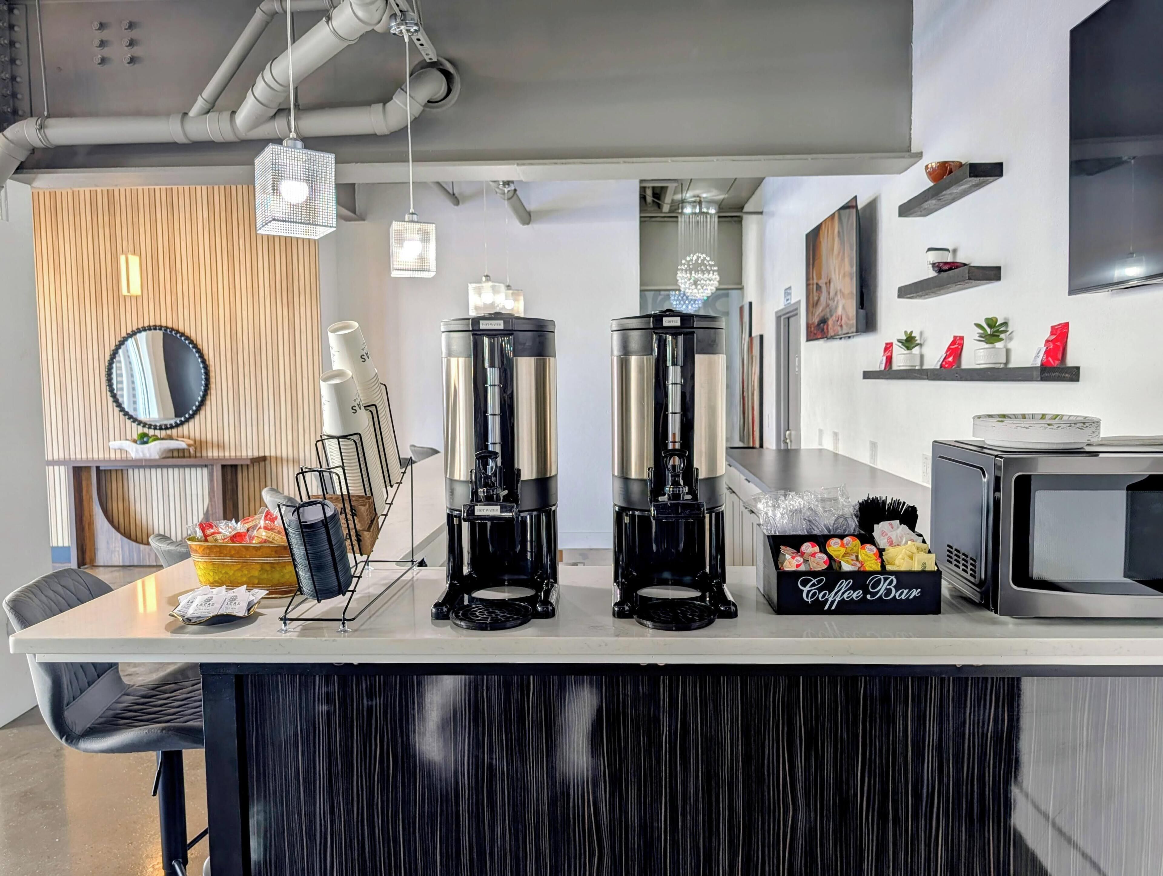 A coffee bar with two espresso machines, a coffee dispenser, and a coffee bar sign.