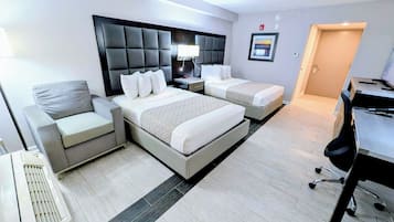 A hotel room with a large bed, two bedside tables, a chair, a desk, and a computer.
