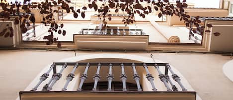 Fachada de edifício com uma varanda central, vários janelões e um guarda-corpo decorativo.