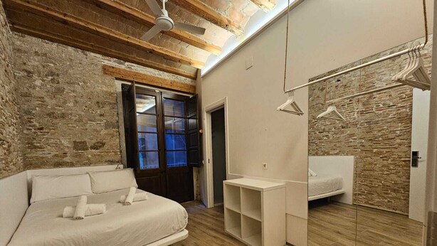 A bedroom with a bed, a bedside table, a mirror, and a wardrobe. - Classic Palau Apartments (Barcelona)