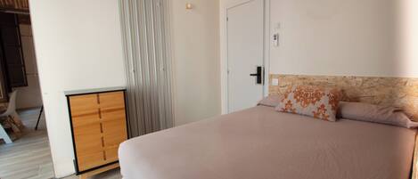 A bedroom with a bed, a wardrobe, and a door.