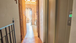 A hallway with a wooden floor, a metal railing, and a door with a green exit sign. - Classic Catedral Apartments  (Barcelona)