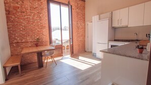 A kitchen with a wooden table, white cabinets, and a view through a glass door. - Classic Catedral Apartments  (Barcelona)