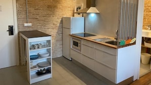 A compact kitchen with a built-in oven, a microwave, and a sink. There is a small cabinet with dishes and a hanging light fixture. - Barcelona Classic Ramblas - Plaza Real (Barcelona)