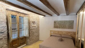 A bedroom with a bed, a stone wall, a wooden door, and a tiled floor. - Barcelona Classic Ramblas - Plaza Real (Barcelona)