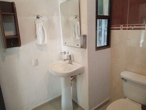 A bathroom with a white sink, a mirror, and a toilet. There is a towel rack above the sink and a small cabinet to the left. - Wonderful 2 bedroom family apartment in Tulum Centro Huanal (Tulum)