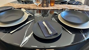 A round dining table with black plates, cutlery, and a folded napkin.