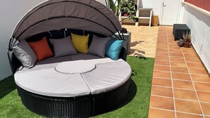 A round outdoor seating area with a canopy, surrounded by artificial grass and a tiled patio.
