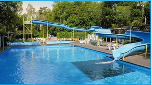 Una piscina con tobogán azul y tobogán acuático.
