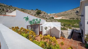 A terrace with a white wall, potted plants, and a table with a chair. - Boutique B&B Casa La Calera 15+/ Caminito del Rey-15 min/Ronda-25 min/Town-5 min (Teba)