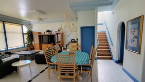 A spacious living room with a dining area, a staircase, and a large window. - Beautiful Riverside Home (T or C)