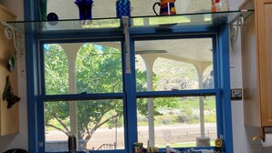 A kitchen with a double sink, a coffee maker, and a window with a view of trees and a landscape. - Beautiful Riverside Home (T or C)