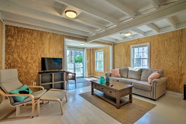 A living room with a wooden wall, a sofa, a coffee table, a TV, and a chair.