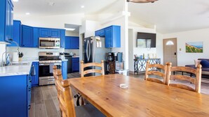 A modern kitchen with blue cabinets, stainless steel appliances, and a wooden dining table. - Cozy Dark Sky Retreat Near Sedona • Hot Tub, Sauna & Views (Cornville)