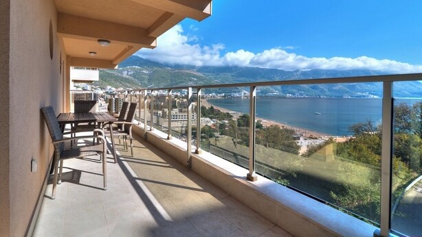 A balcony with a view of a lake and mountains, furnished with chairs and a table. - Sea View Apartments MonteBook (Becici)