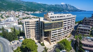 A multi-story hotel with a modern design, located near a coastal area with a view of the sea and mountains. - Sea View Apartments MonteBook (Becici)