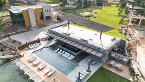 A modern building with a rooftop pool, outdoor seating, and a landscaped garden. - PK Juniper Overlook | Brand new home! | Sleeps 17 w 2 living rooms, kayaks/games (Graford)