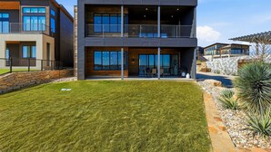 A modern two-story building with a flat roof, large windows, and a balcony. - PK Juniper Overlook | Brand new home! | Sleeps 17 w 2 living rooms, kayaks/games (Graford)