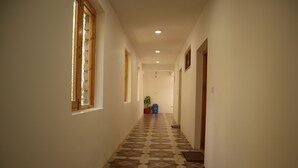 Um corredor com piso estampado, um vaso de planta e uma lixeira.