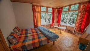 Um quarto com cama, poltrona e janela com cortinas.