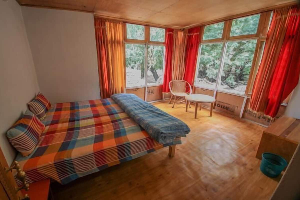A room with a bed, a chair, and a window with curtains.