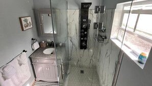 A modern bathroom with a glass-enclosed shower, a vanity with a sink, and a mirror. - Sunburst Studio (Caicos Islands)
