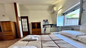 A hotel room with a bed, two towels, a wooden wardrobe, a cabinet, and a window with a view. - Apartment with all amenities 50 meters from the sea. Breathtaking view (Lido Riccio)