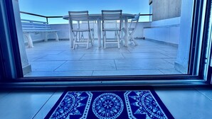 A view from inside a room to an outdoor balcony with a table and chairs. - Apartment with all amenities 50 meters from the sea. Breathtaking view (Lido Riccio)