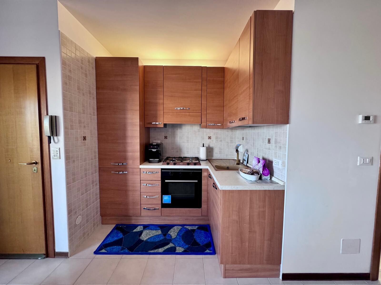 A compact kitchen with wooden cabinets, a built-in oven, and a gas stove.