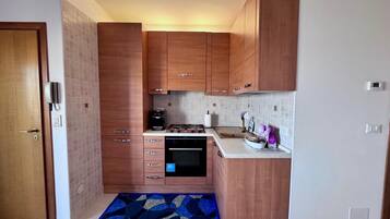 A compact kitchen with wooden cabinets, a built-in oven, and a gas stove.