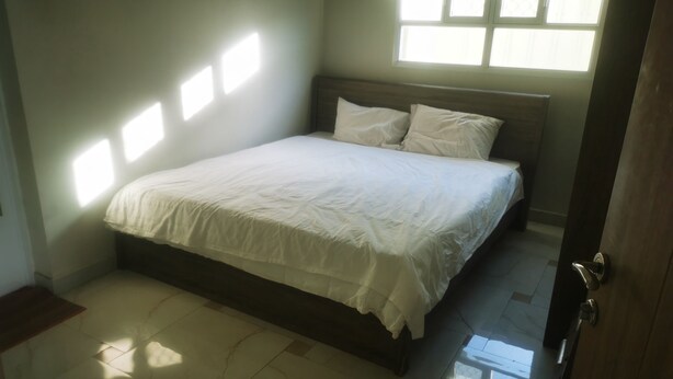 A bedroom with a bed, a window, and a door.