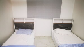 Two single beds with wooden headboards, white bedding, and a tiled floor.