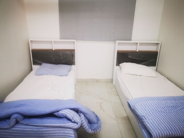 Two single beds with wooden headboards, white bedding, and a tiled floor.