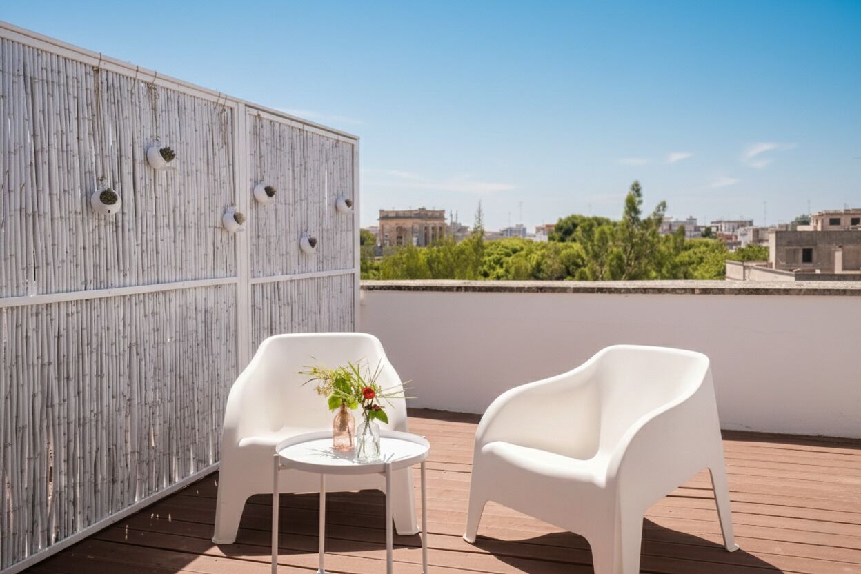 Een terras op het dak met twee witte plastic stoelen, een kleine ronde tafel met een vaas bloemen, en een bamboe wand met ronde uitsparingen.