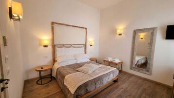 Un dormitorio con cama de madera, mesitas de noche, un espejo y luces fijadas en la pared.