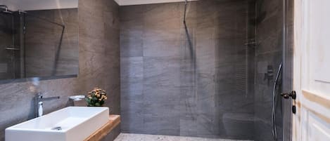 A modern bathroom with a rectangular sink, a glass shower enclosure, and a toilet.