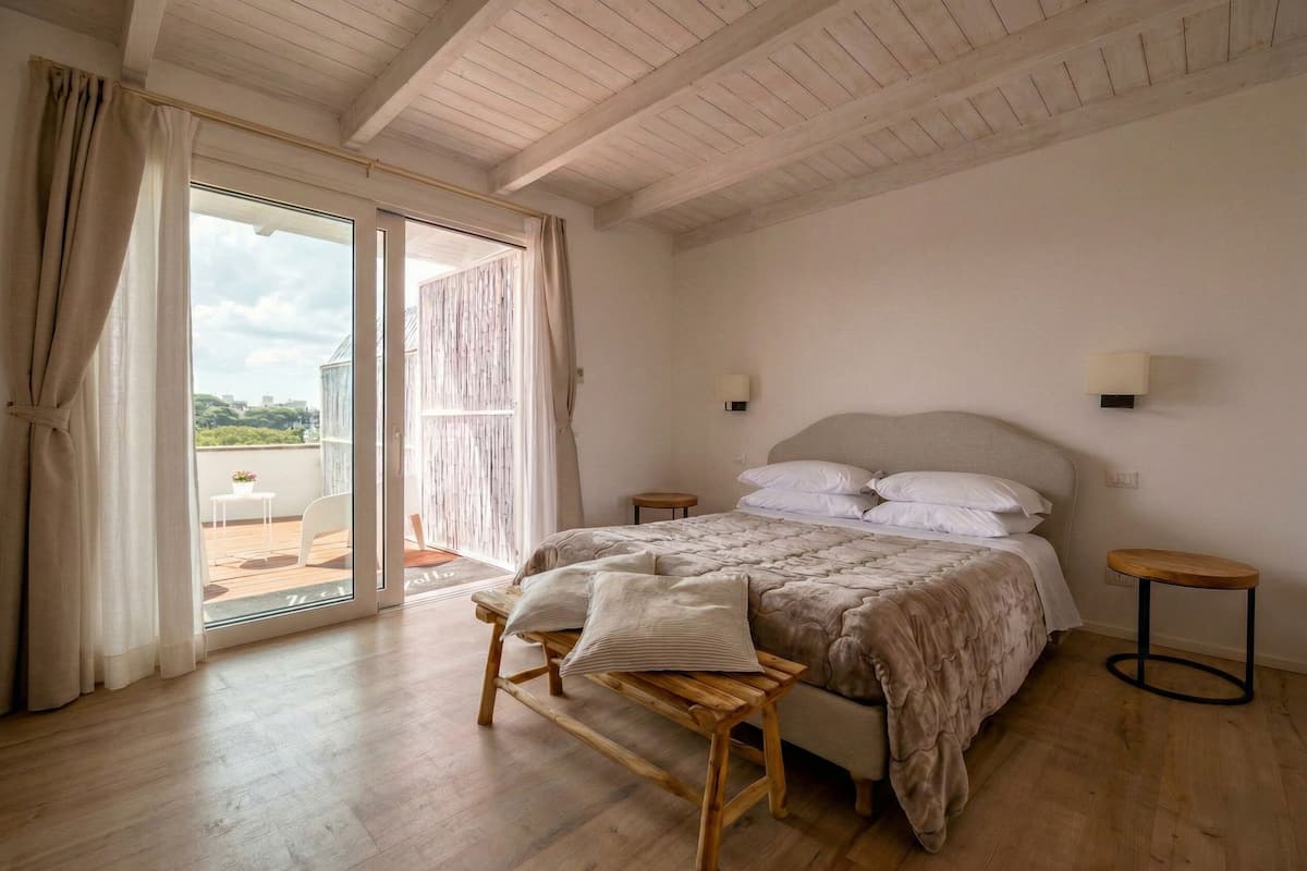Un dormitorio con una cama grande, un banco de madera y un taburete pequeño.