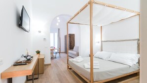 Een moderne slaapkamer met een hemelbed, een houten bureau en een aan de muur bevestigde televisie.