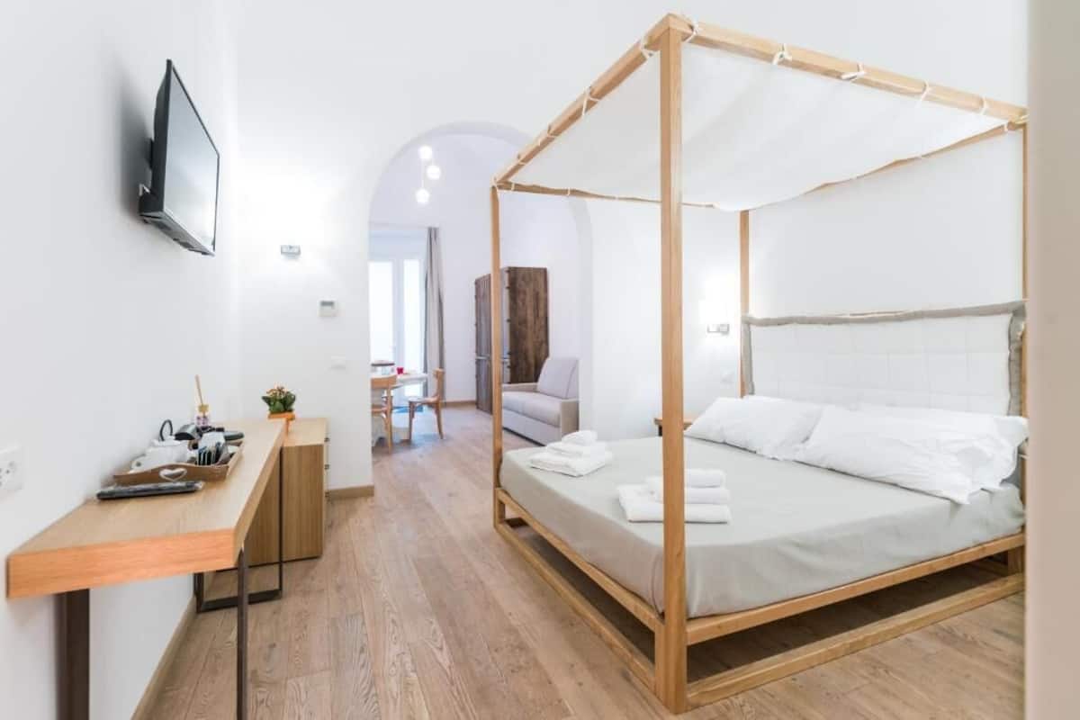 Un dormitorio moderno con una cama con dosel, un escritorio de madera y un televisor montado en la pared.