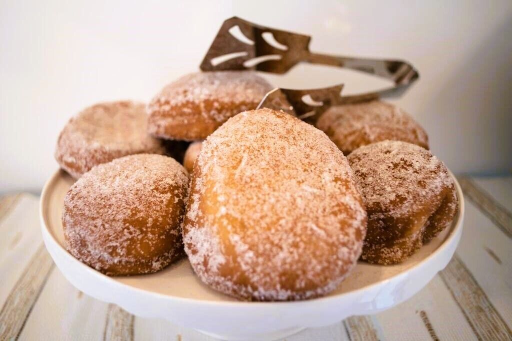A plate of sugar-dusted pastries on a white plate.