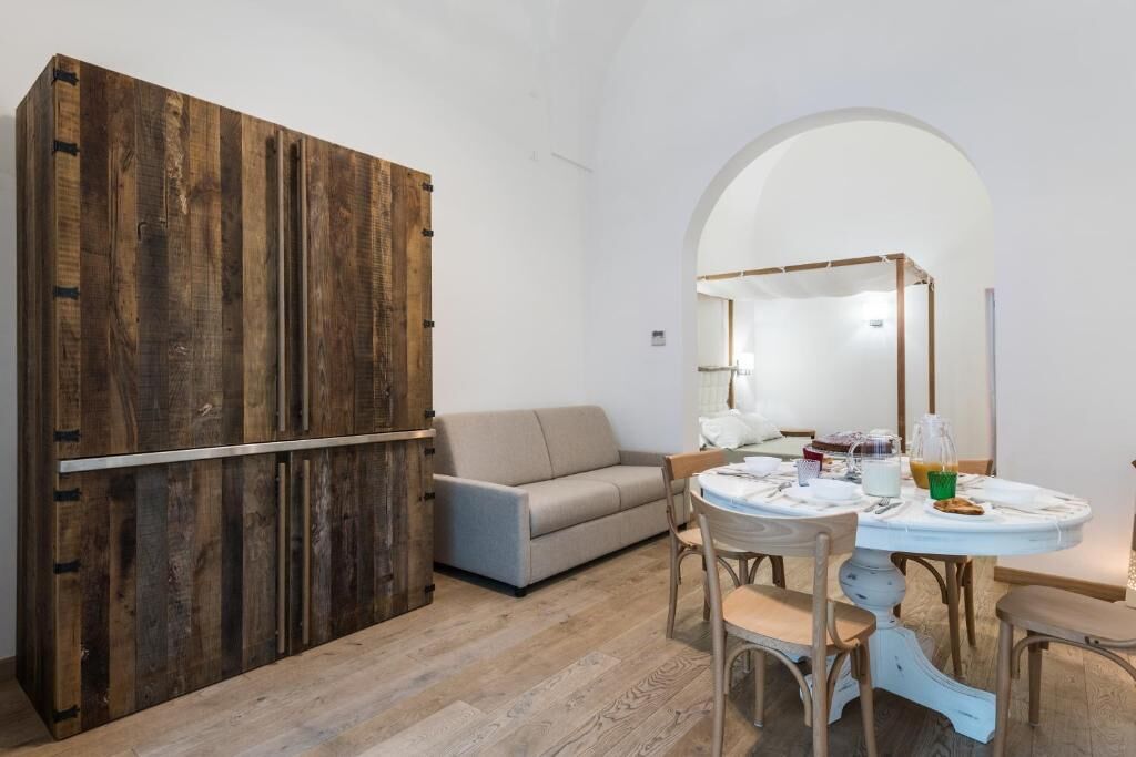 Une pièce comprenant une armoire en bois, un canapé, une table à manger avec des chaises et un miroir.