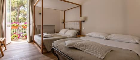 Una cama con dosel, dos mesitas de noche y vistas a un balcón con flores.