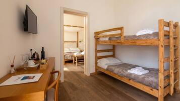 A room with a bunk bed, a desk with a chair, and a television mounted on the wall.