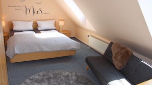 A bedroom with a bed, two bedside tables, a nightstand, a sofa, and a radiator.