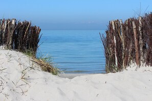 A sandy beach with a wooden fence leading to the water.